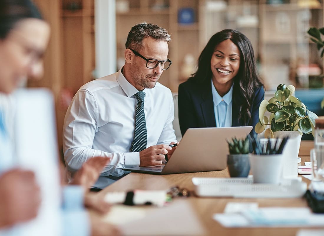 Financial Services - Two Smiling Diverse Businesspeople Using a Laptop Together at Wo